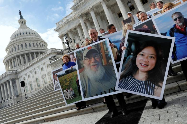 Lãnh đạo phe thiểu số tại Thượng viện Mỹ Chuck Schumer (trung tâm) và các Thượng nghị sĩ khác của Đảng Dân chủ đứng trước toà nhà Quốc hội Mỹ và cầm ảnh chân dung những người bị ảnh hưởng do chính phủ đóng cửa ngày 16/1. Ảnh: Reuters.