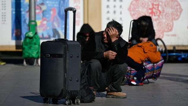 Người đàn ông ngồi chờ khi trên đường về quê ăn Tết. Ảnh: Getty.