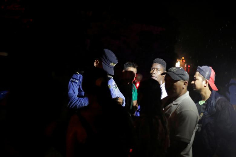 Một cảnh sát kiểm tra thẻ căn cước của công dân Honduras tại chốt kiểm soát ở Cofradia, Honduras, ngày 14/1.