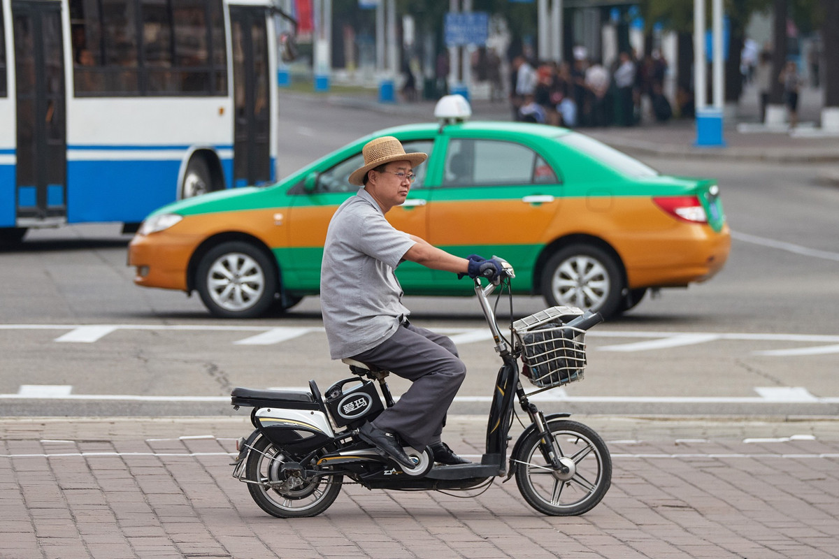 Người dân Triều Tiên đi xe đạp điện trên đường phố.