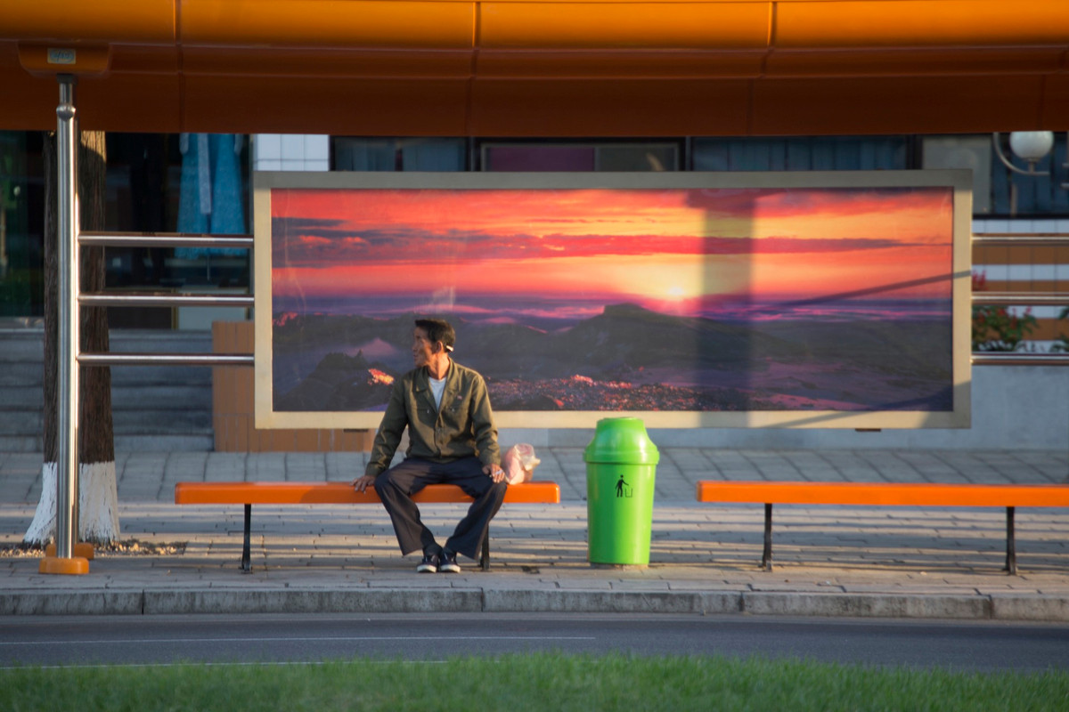 Một người đàn ông ngồi chờ tại bến xe.