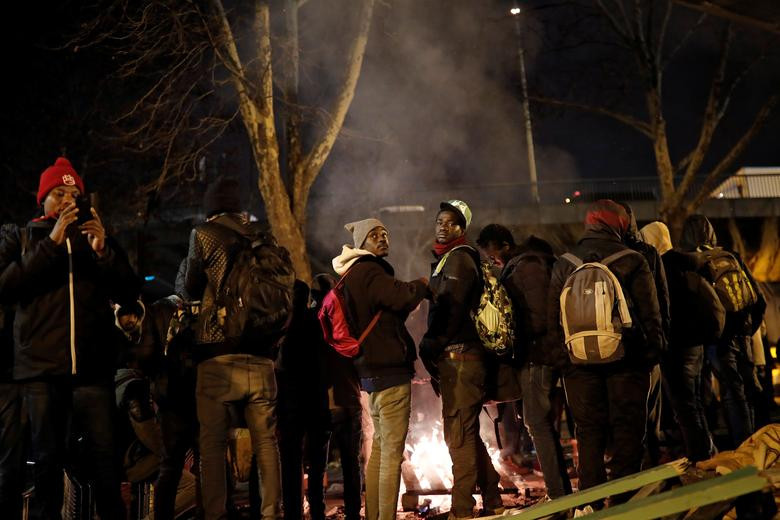 Những người dân nhập cư đốt lửa sưởi ấm trong lúc chờ đợi.