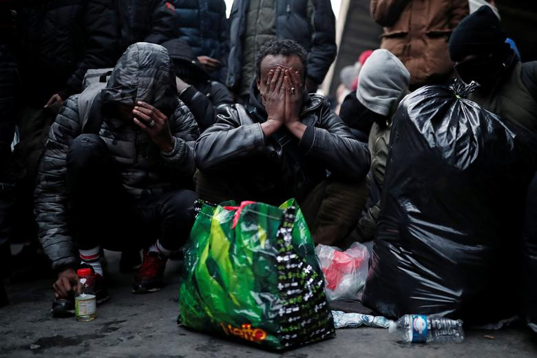 Các di dân ngồi chờ trong quá trình sơ tán khỏi khu trại tị nạn dưới cầu Porte de la Chapelle.