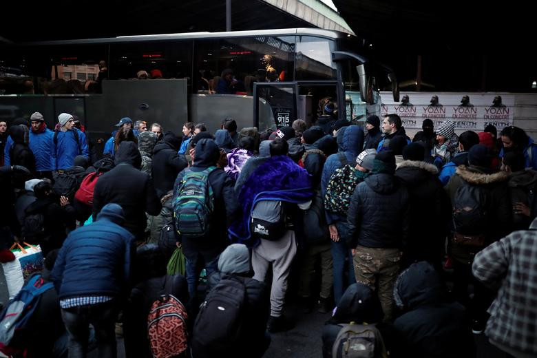 Nhiều di dân lên xe buýt sau khi được cảnh sát Pháp sơ tán khỏi khu trại hôm 29/1.