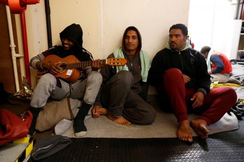 Một di dân chơi đàn ghi-ta trong lúc nghỉ ngơi trên tàu cứu hộ. Họ đã lênh đênh trên biển suốt 2 tuần qua.