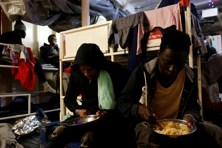 Các di dân ngồi ăn trong không gian chật chội trên tàu Sea-Watch ngày 3/1.