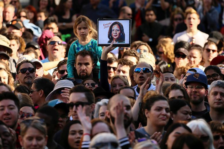 Người phụ nữ giơ cao tấm hình Thượng nghị sĩ Harris khi lắng nghe Thượng nghị sĩ Kamala phát biểu trong cuộc vận động tranh cử ở Oakland.