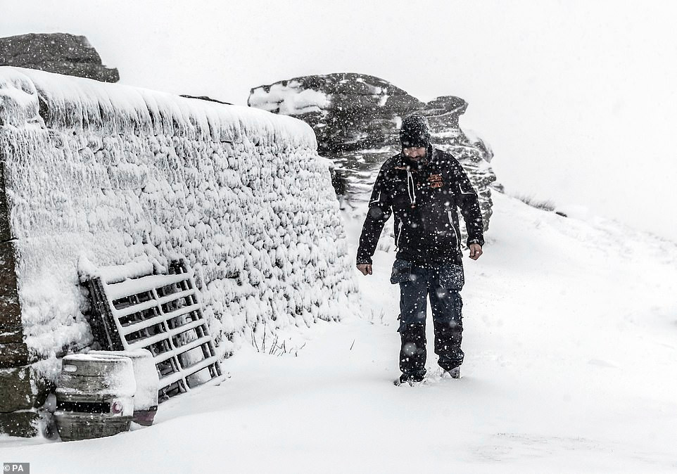 Người đàn ông đi bộ dưới trời mưa tuyết ở Tan Hill Inn, North Yorkshire.