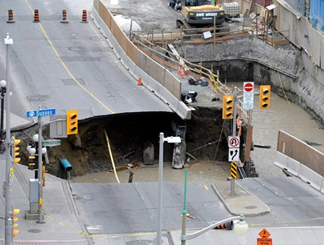 Hố nước lớn trên đường Rideau, cạnh trung tâm mua sắm Rideau ở Ottawa, tỉnh bang Ontario, Canada. Một chiếc xe tải bị rơi vào hố, gây rò rỉ xăng. Bên cạnh đó, người dân trong các tòa nhà xung quanh khu vực xảy ra sự cố cũng phải sơ tán. (Ảnh: Justin Tang/Canadian Press)