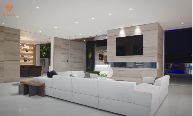 Phòng khách ấn tượng với không gian rộng rãi, sofa tiện nghi, TV giải trí, cùng hệ thống đèn âm trần sang trọng.