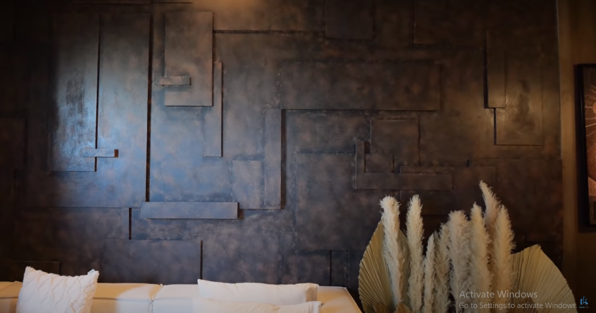 Điểm nhấn trong phòng khách là bức tường ốp gỗ nhưng được sơn hiệu ứng khiến khách ngỡ như làm bằng kim loại.