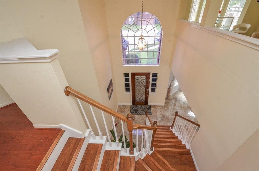 Cầu thang đặt đối diện cửa ra vào, lát gỗ tự nhiên sáng màu.