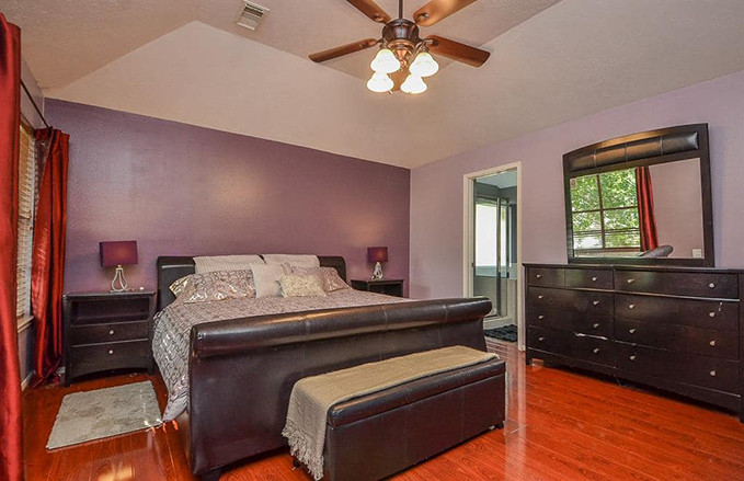 Nhà có 3 phòng ngủ, trong đó phòng ngủ chính rộng hơn so với các phòng còn lại, nổi bật với tường sơn màu tím trầm, trần trắng, sàn lát gỗ.