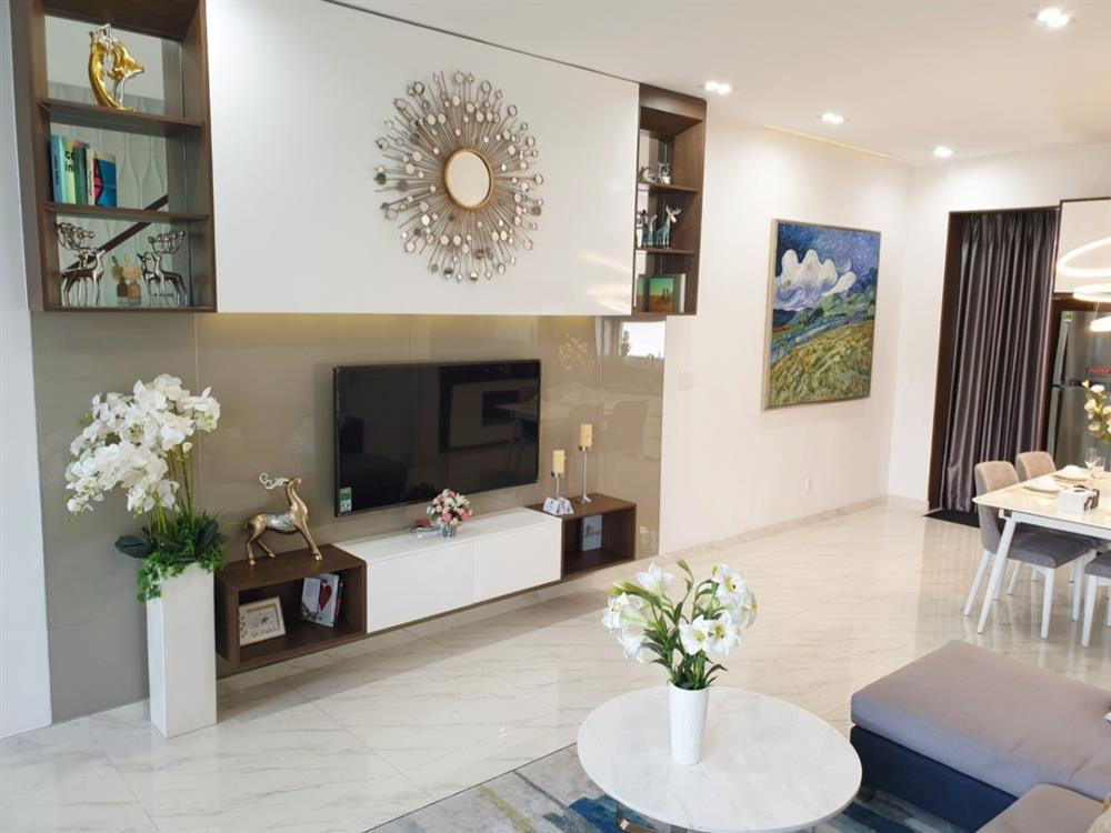 Tầng trệt là không gian phòng khách, phòng ăn và khu vực bếp. Phòng khách trang trí bằng những bình hoa trắng và tranh ảnh. Ảnh: Suckhoedoisong