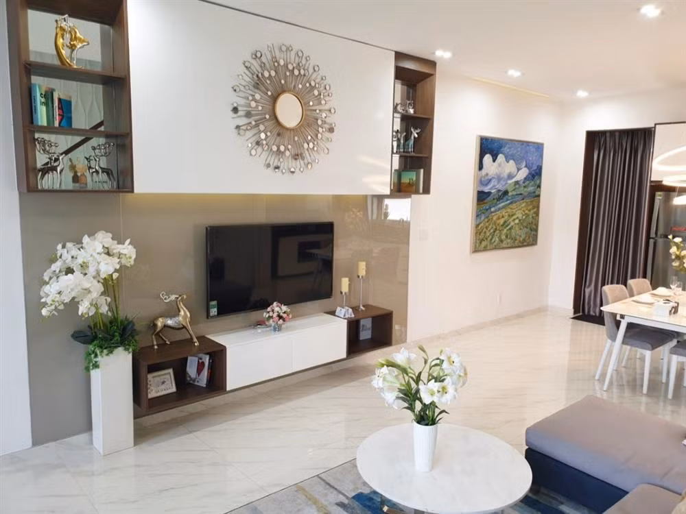 Tầng trệt là không gian phòng khách, phòng ăn và khu vực bếp. Phòng khách trang trí bằng những bình hoa trắng và tranh ảnh. Ảnh: Suckhoedoisong