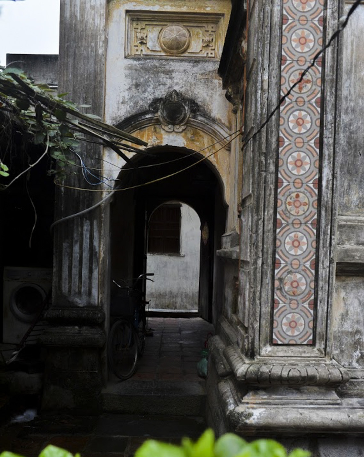 Lối vào nhà chỉ là một chiếc cổng nhỏ hẹp, trước cửa có họa tiết hình quả trám đặc trưng của kiến trúc Pháp. Ảnh: Dân Việt