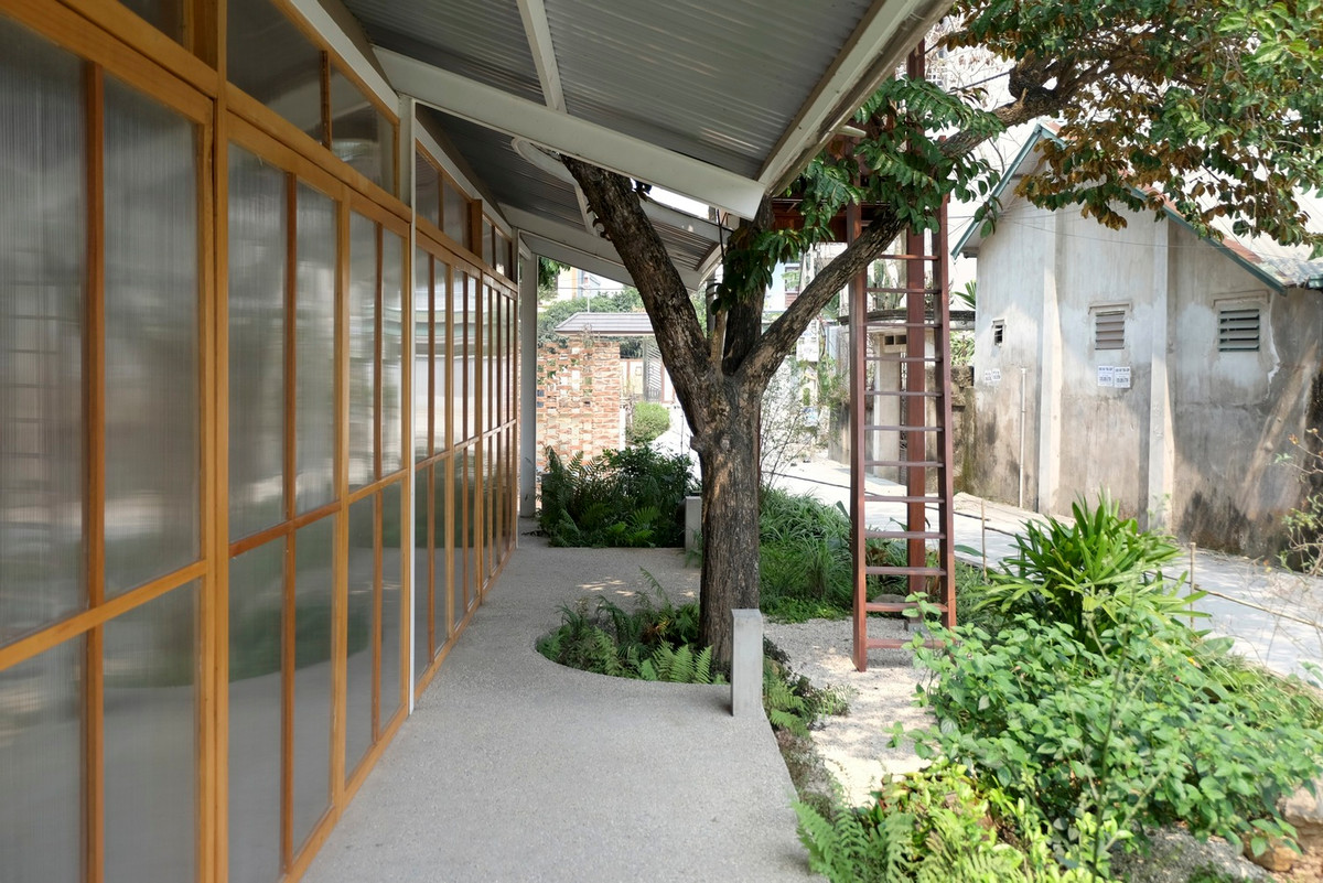 Nhà hàng và ngôi nhà cổ được ngăn cách bởi một lối đi nhỏ với hàng tre và gạch đỏ xen kẽ.