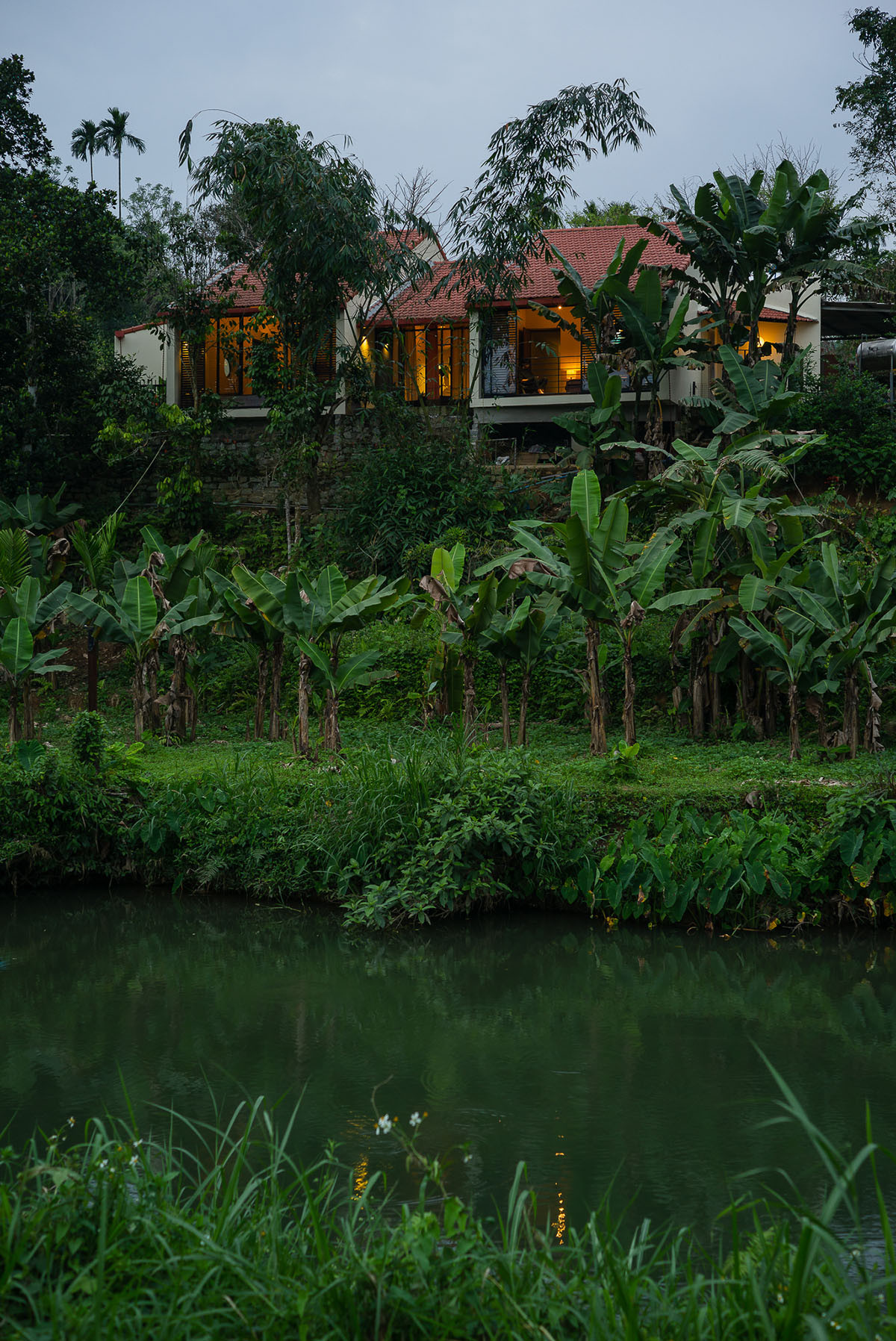  Ngôi nhà nằm trên một đồi đốc, dưới chân là vườn cây ăn trái, xung quanh là nhũng ngọn núi và cánh đồng xanh mướt.