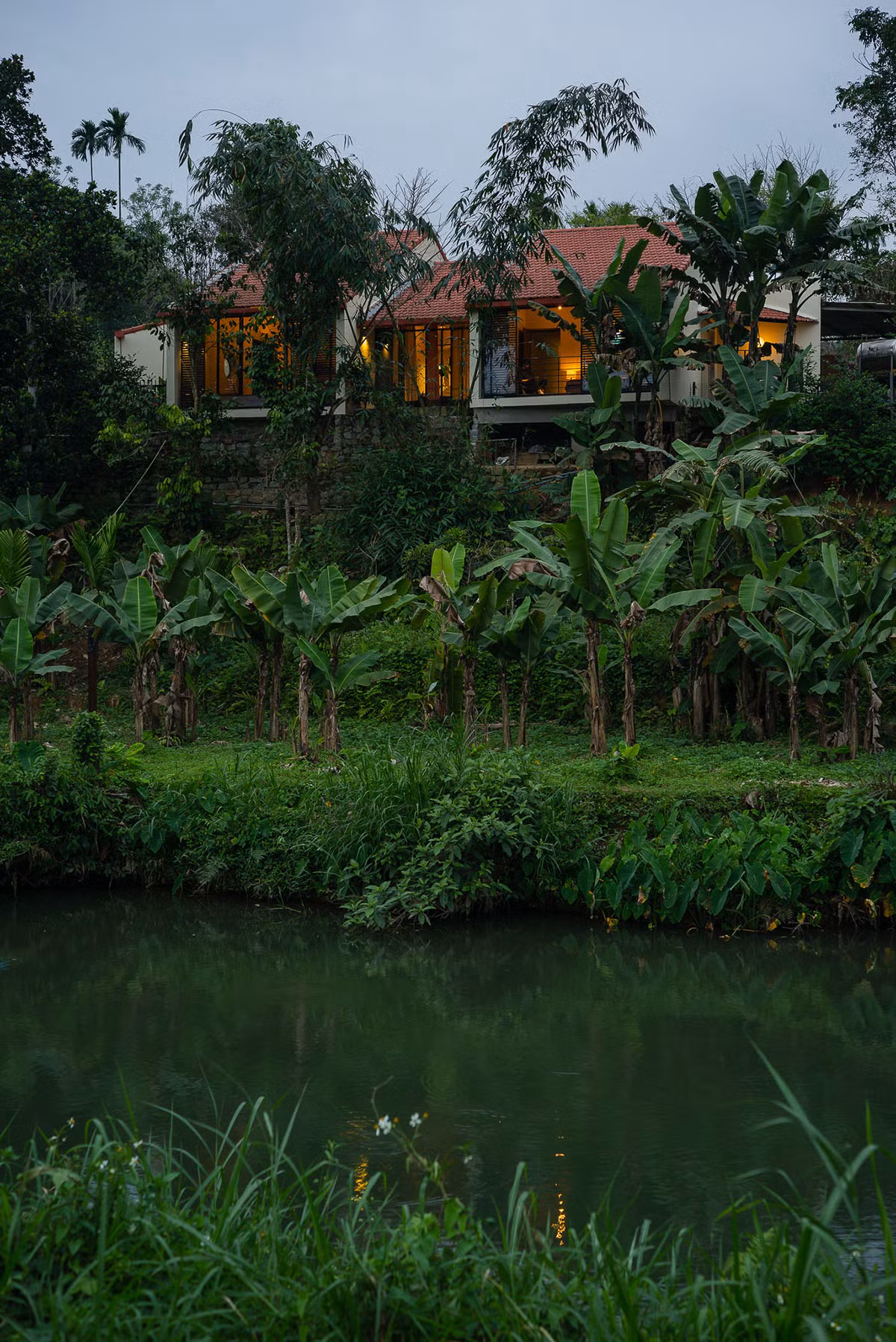  Ngôi nhà nằm trên một đồi đốc, dưới chân là vườn cây ăn trái, xung quanh là nhũng ngọn núi và cánh đồng xanh mướt.