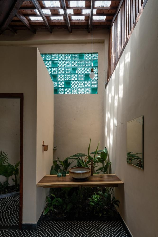 Phòng tắm được tối ưu ánh sáng và gió trời nhờ các ô gạch kính đan xen trên mái, cửa sổ gạch bông gió và hệ lam gỗ. Nguồn ảnh: Quang Dam