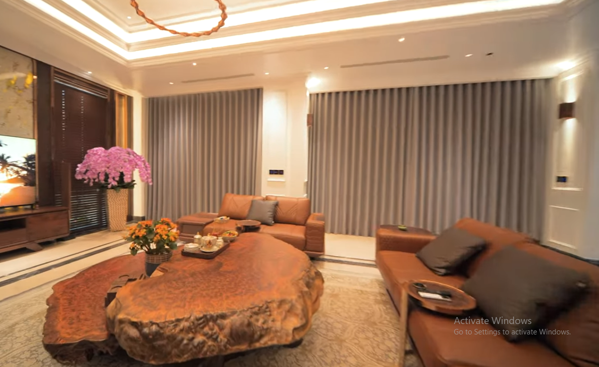 Phòng khách nổi bật với bộ sofa làm bằng da bò tót nhập khẩu và bàn trà bằng gỗ nu xá xị.