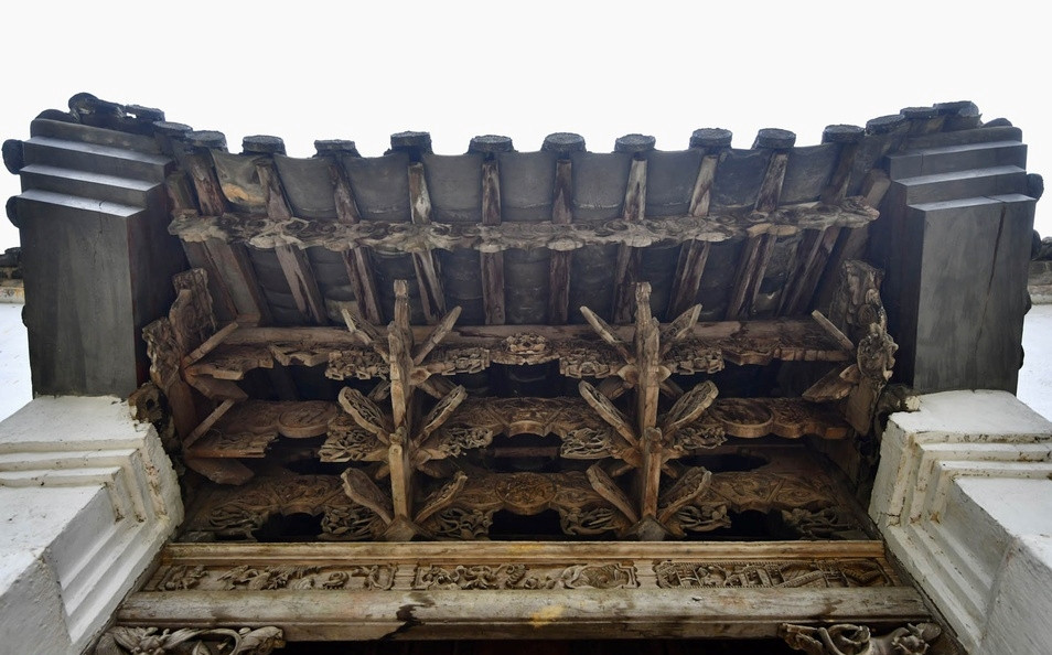 Hệ kết cấu gỗ dưới mái cổng uốn lượn theo hình cánh dơi của người Mông mang biểu tượng chữ “Phúc”. Ảnh: Zing