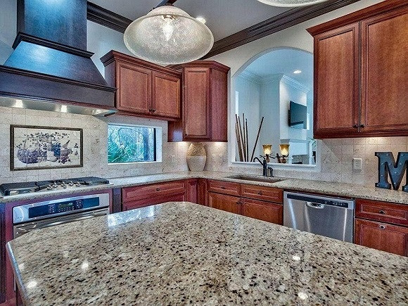 Phòng bếp sử dụng tủ gỗ ấm cúng và mặt đá sang trọng.