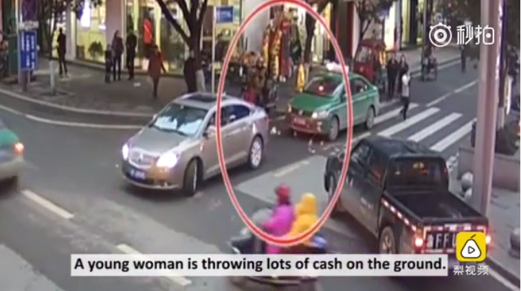 Những hình ảnh từ camera cho thấy người phụ nữ vừa bước qua vạch kẻ dành cho người đi bộ vừa thò tay vào túi xách, bốc từng nắm tiền rồi thả xuống đường. Ảnh chụp màn hình