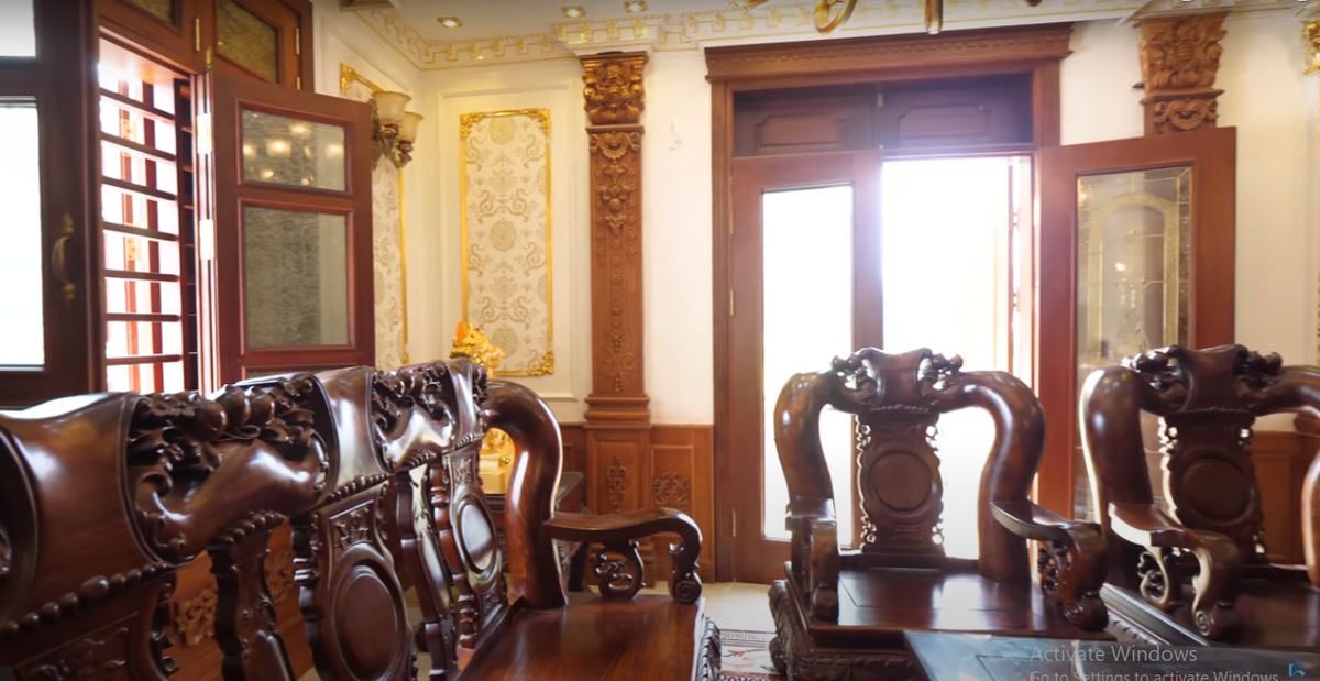 Phòng khách nổi bật với bộ bàn ghế đồ sộ bằng gỗ lim.