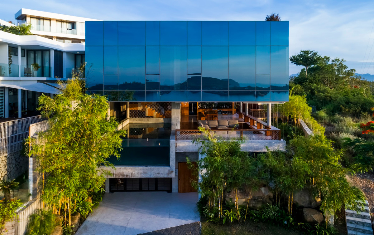 Điểm nhấn của biệt thự là khu bể bơi treo lơ lửng ngay lối đi vào nhà, có 3 mặt tường bê tông, mặt còn lại là kính cường lực.