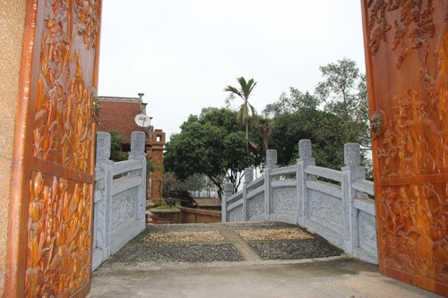 Bước qua cánh cổng là chiếc cầu đá dẫn vào ngôi nhà gỗ mít. Hai bên thành cầu làm từ đá ghép mộng. Ảnh: Zing