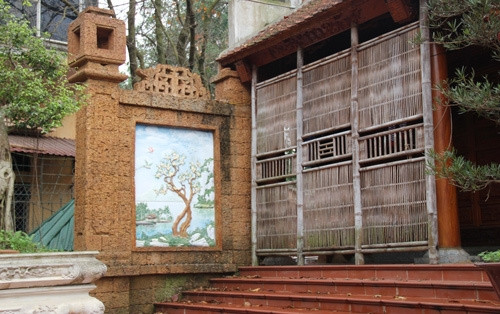 Trước hiên nhà có tranh tường sứ và rèm tre đậm chất dân tộc. Ảnh: Vietnamnet