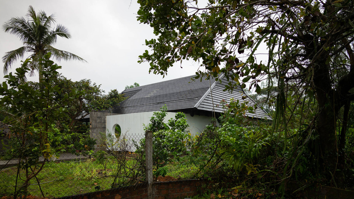 Nằm lọt thỏm giữa rừng keo tại huyện Quế Sơn (Quảng Nam), ngôi nhà cấp 4 nổi bật với khối mái lớn bao phủ lên toàn bộ công trình.