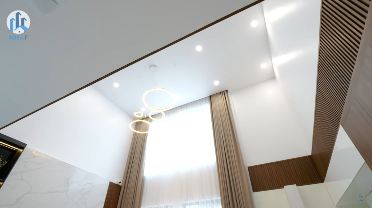 Phòng khách có khoảng thông tầng lớn, phía trên trang trí đèn bắt mắt.