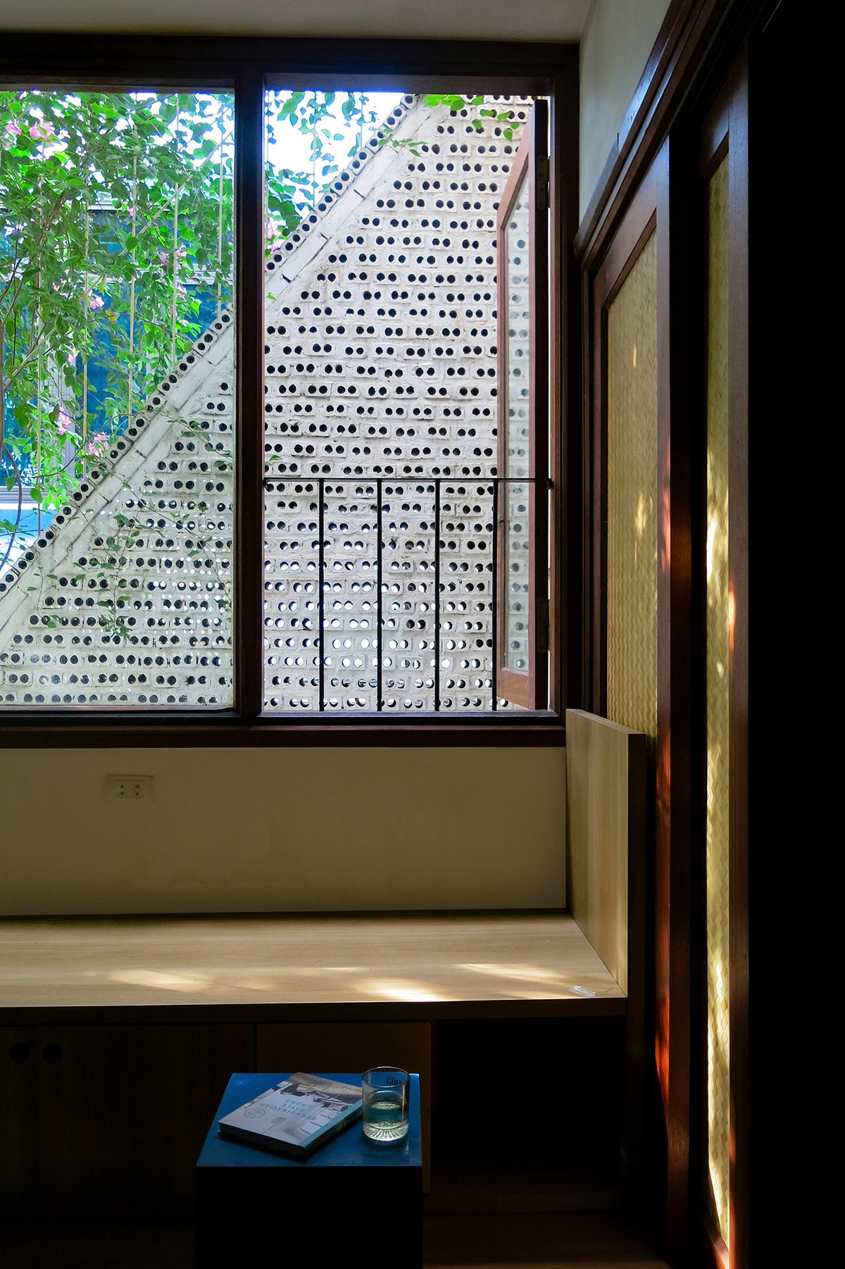 Phòng khách được thiết kế cửa kính lớn và cửa sổ nhìn ra mặt tiền gạch lỗ.