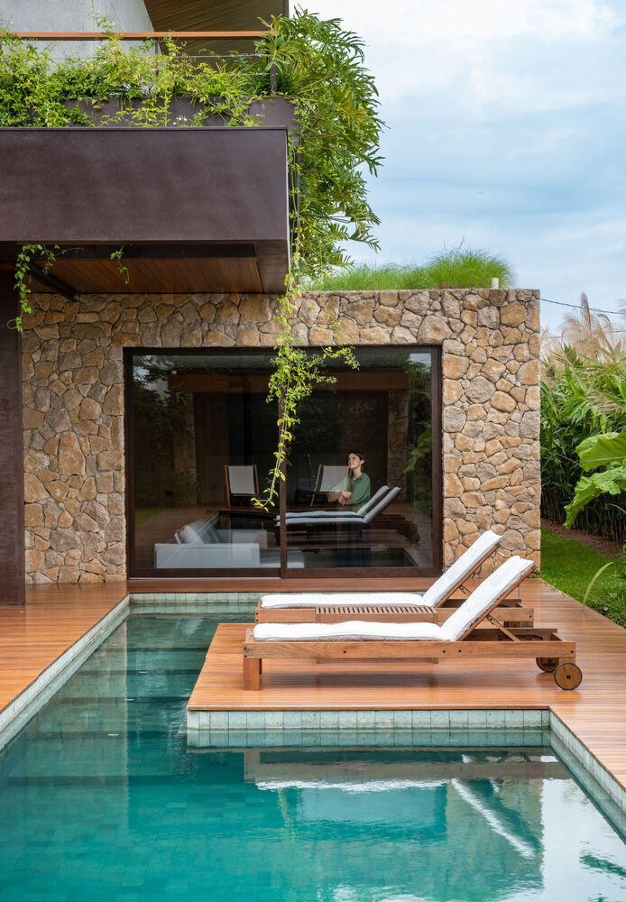 Khu vực bể bơi và sân vườn sau nhà được bao bọc bởi hai lớp hàng rào cây xanh.