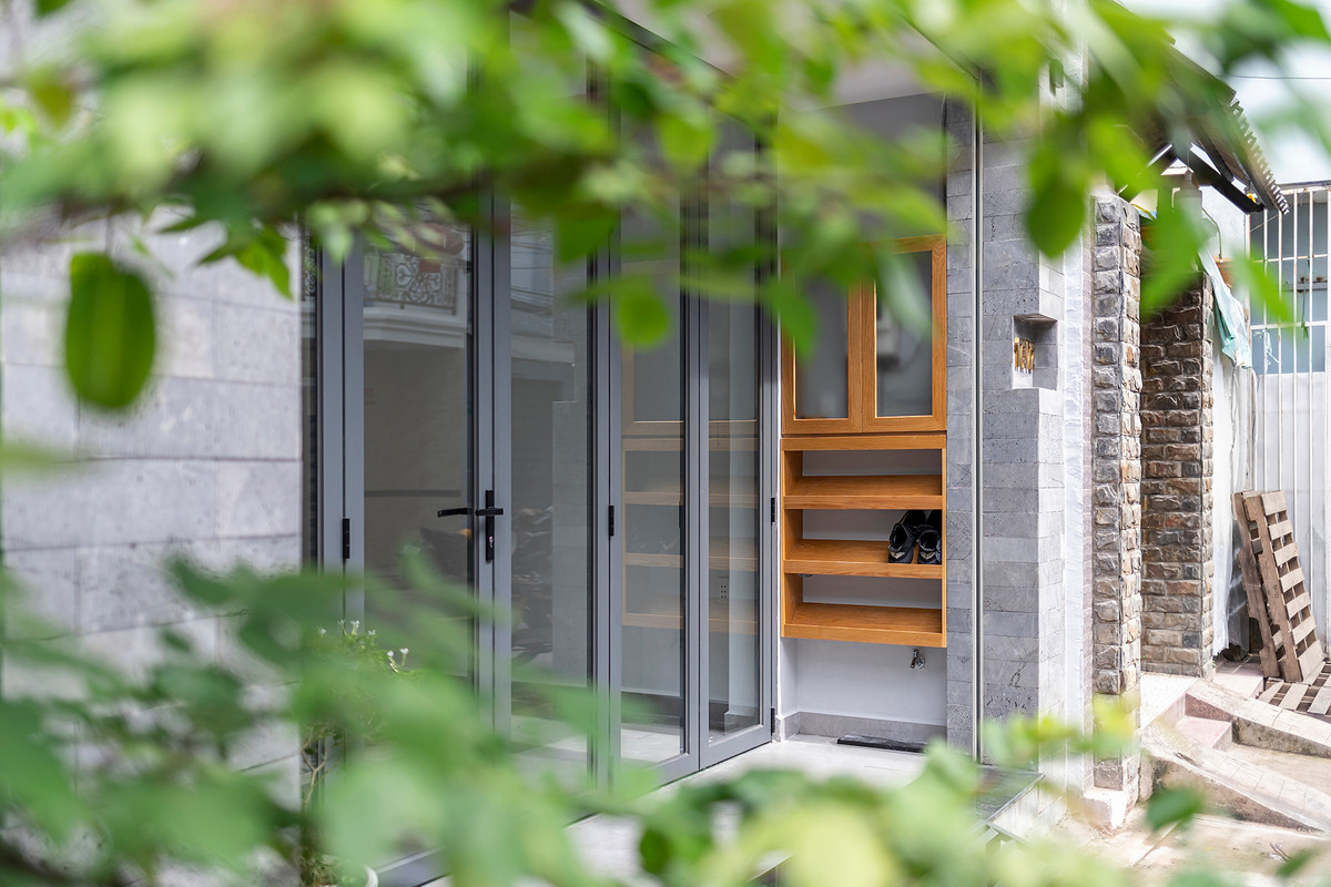 Ngoài không gian, vật liệu cũng được kiến trúc chăm chút trong từng chi tiết. Hệ thống đá tổ ong xám ốp tường mặt tiền – giữa nhà – phía sau nhà, tạo sự liền mạch và kết nối trong ngôn ngữ kiến trúc.