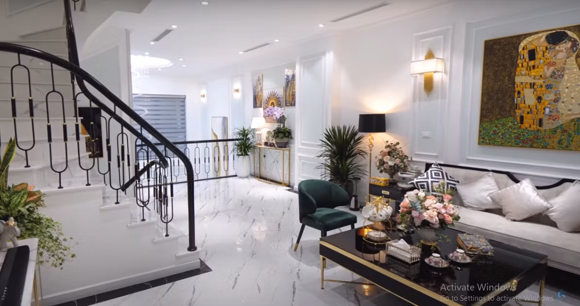 Phòng khách sử dụng gam màu trắng chủ đạo, xen lẫn một số chi tiết màu đen và mạ vàng làm điểm nhấn.