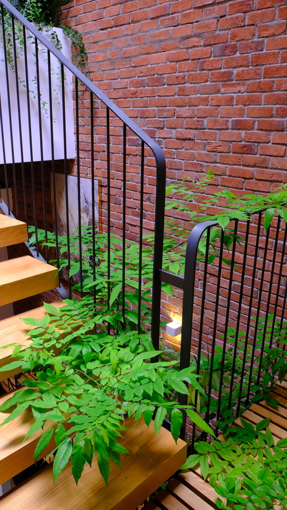 Bậc thang gỗ với kết cấu thép, hành lang trước phòng bằng lam gỗ, mảng gạch đỏ cho toàn bộ tường khu vực thông tầng, nơi đây như khoảng không gian kết nối tất cả các khu vực trong nhà.