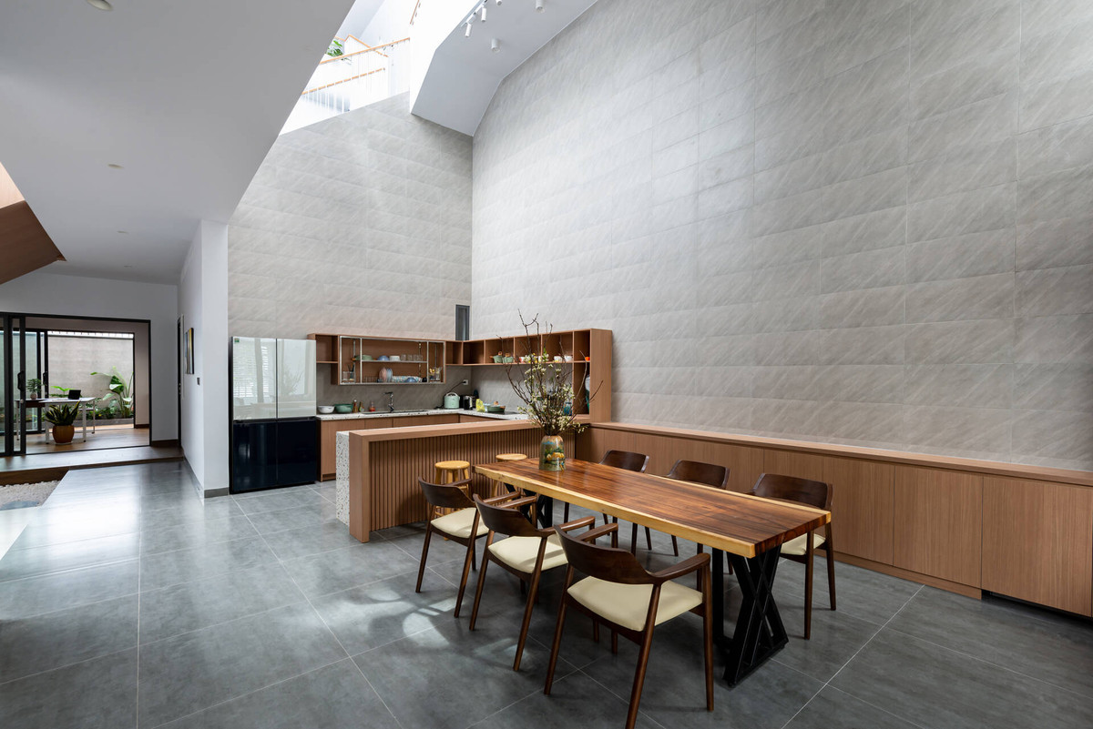 Bếp và bàn ăn được thiết kế liền mạch, nằm ngay dưới khoảng thông tầng rộng thoáng.