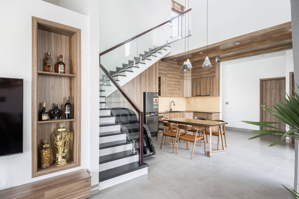 Khu bếp và bàn ăn được bố trí dưới khoảng thông tầng, nhìn ra sân vườn thông qua ô cửa sổ.