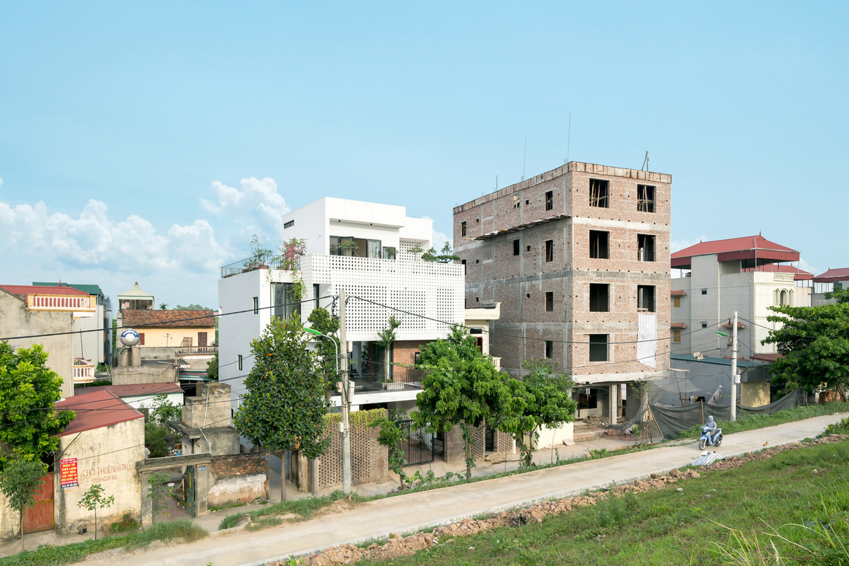 Nằm ngay chân đê sông Đáy, phường Yên Nghĩa (quận Hà Đông, Hà Nội), ngôi nhà mở ra một góc nhìn 40 độ lên mặt đường chính triền đê với ba cao độ mặt đường hạ cấp xuống nền công trình.