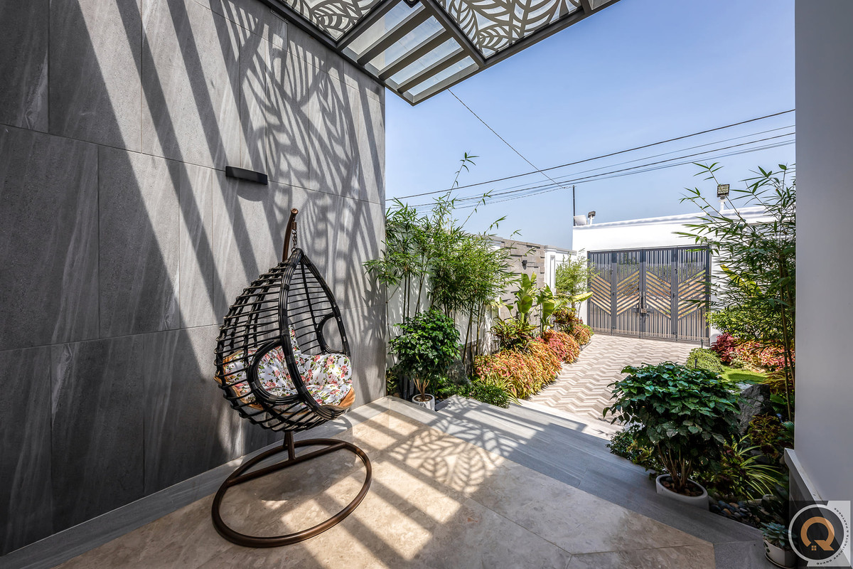 Lối dẫn vào nhà ốp gạch, xung quanh tô điểm bằng nhiều chậu cây đa dạng.