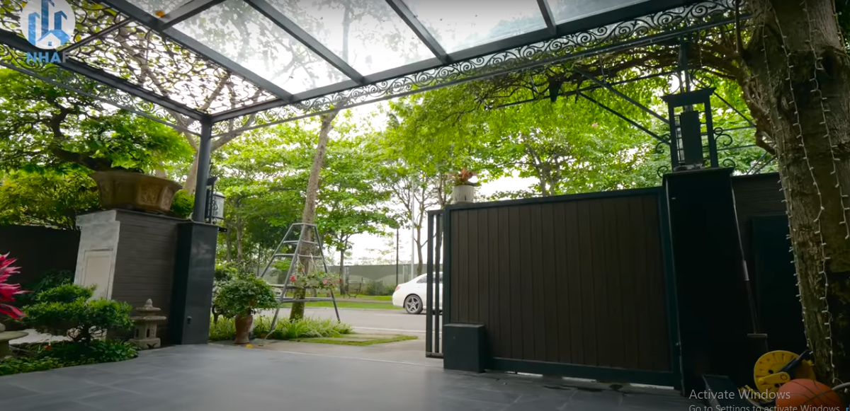 Sân vườn trồng nhiều cây xanh, phía ngoài là giàn hoa giấy toả bóng mát.