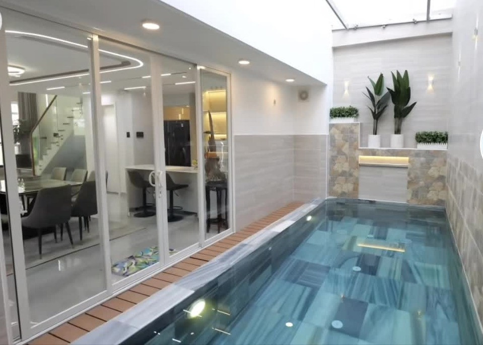 Trong nhà còn có bể bơi lớn. Xung quanh hồ được ốp đá, thiết kế thác nước nhỏ và trồng cây xanh. Ảnh chụp màn hình