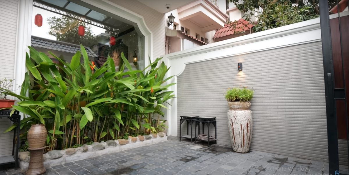 Bước qua cánh cổng gỗ là khoảng sân nhỏ, trồng nhiều cây xanh.