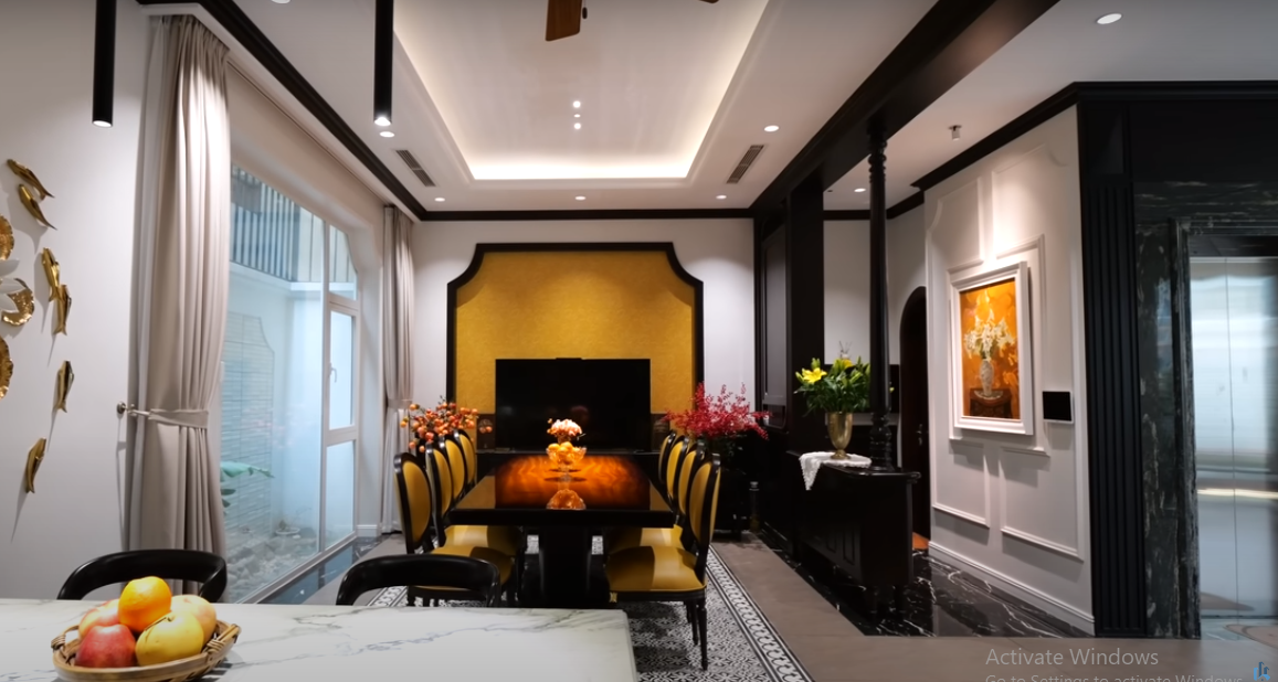 Bàn ăn và khu bếp liên thông nhau, nhìn thẳng ra hồ cá qua hệ cửa kính lớn.