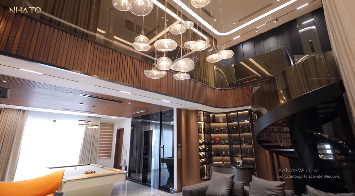 Tại khu vực thông tầng, gia chủ làm trần cao 7 m tạo độ thoáng đãng, “kéo giãn” không gian với bàn tủ rượu, bar mini cũng như trưng bày nhiều đồ sưu tập.