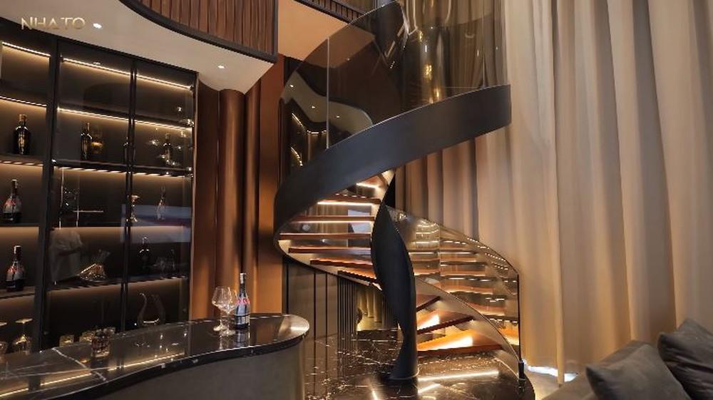 Cầu thang sắt uống cong phối với bậc kính, ánh sáng cảm biến tăng thêm độ sang trọng.