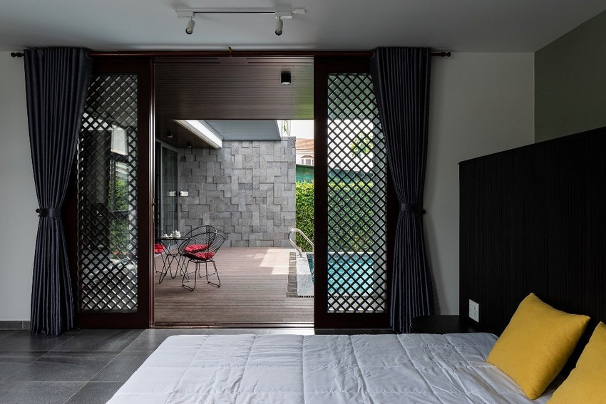 Phòng ngủ gần không gian chung nhưng vẫn có sự riêng tư bởi tấm màn treo và khung cửa sắt.